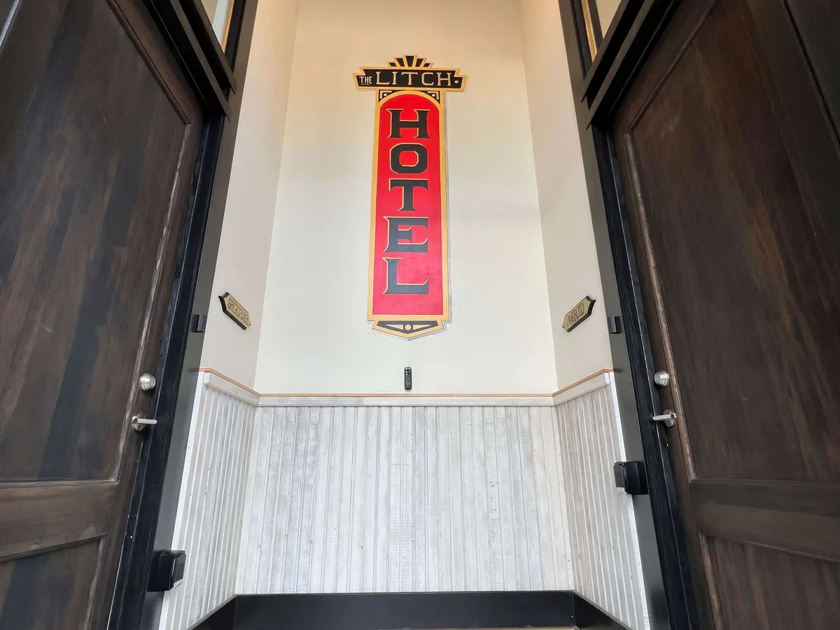 The warmly lit entryway of The Litch Hotel features a nostalgic sign welcoming guests. This space provides a first impression of the area's historic hospitality and echoes the vintage charm found throughout downtown Enterprise.